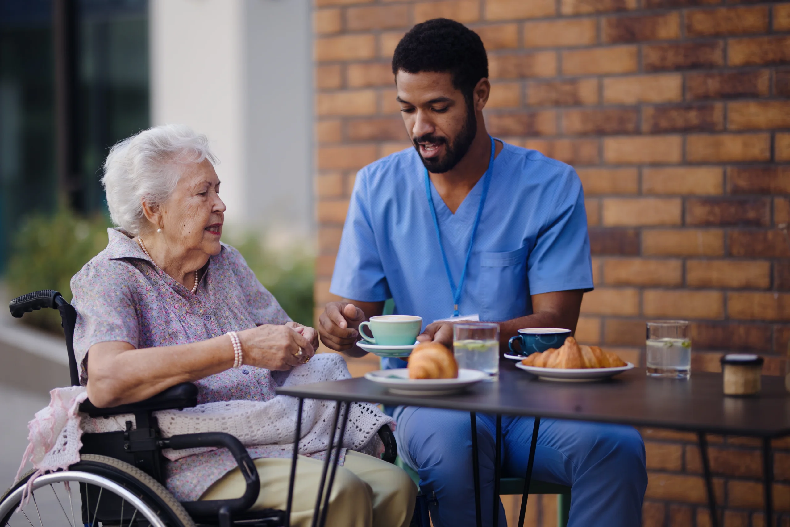 Caregiver having breakfast with his client at cafe.