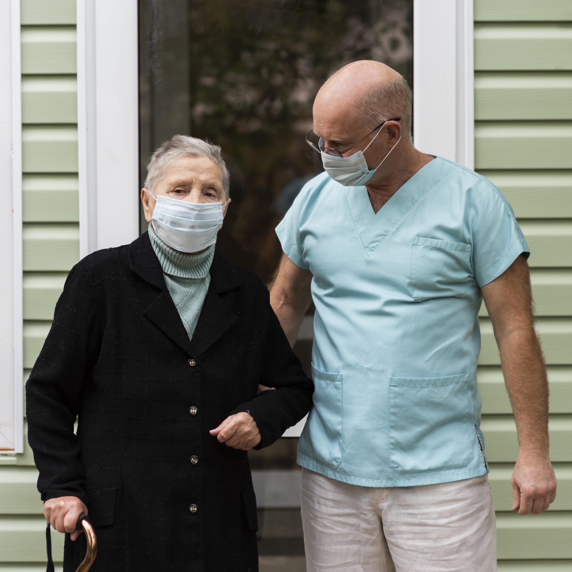 male-nurse-senior-woman-with-cane-nursing-home-scaled