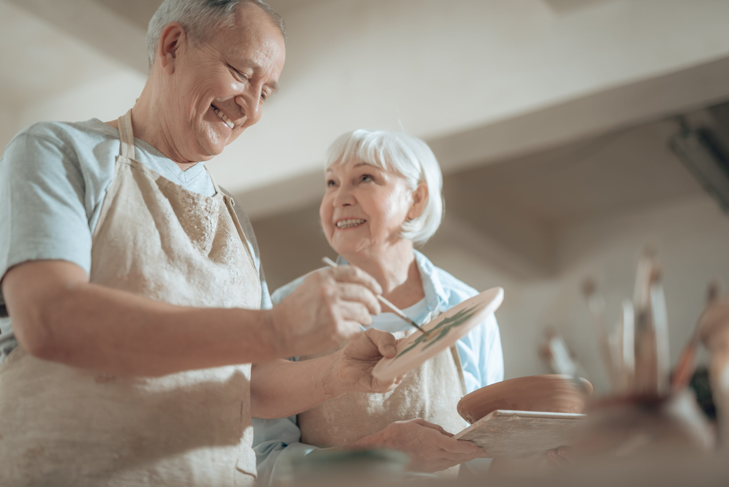 Low angle of smiling elderly craftsman painting decorative plate in workshop Portrait of a smiling family on an autumns day